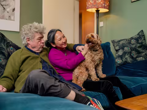 Couple sits on the sofa with a dog