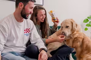 A man and woman feed their dog treats